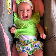élia participe au concours pour gagner de l'argent avec cette photo : baby, smiling, infant, car_seat, headband, green_clothing, floral_shorts, cute, happy, child, indoors, seat, pink_cushion, gray_fabric, playful, portrait, person, young_child, cheerful, baby_girl