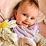 élia a rejoint le concours — aidez-le/la à gagner de superbes lots ! baby, smiling, face, child, plush_toy, blanket, purple_bib, soft_toy, green_toy, pink_background, cute, infant, happy, indoors, closeup, person, toddler, playtime, comfort, cozy
