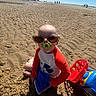 Ellijah is registered to the contest to win money with this photo: toddler, child, beach, sand, sunglasses, pacifier, toy, toy_truck, red_shirt, blue_sky, sunny, outdoor, playing, summer, barefoot, shadow, person, relaxation, vacation, fun