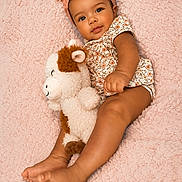 Rose-Mary joined the competition — help win amazing prizes! baby, infant, child, headband, stuffed_animal, plush_toy, blanket, soft_texture, floral_outfit, cute, lying_down, barefoot, smiling, portrait, indoors, skin, face, hands, feet, toddler