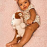 baby, infant, child, headband, stuffed_animal, plush_toy, blanket, soft_texture, floral_outfit, cute, lying_down, barefoot, smiling, portrait, indoors, skin, face, hands, feet, toddler