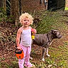 Ricki joined the competition — help win amazing prizes! toddler, child, dog, leash, outdoor, grass, tree, curly_hair, pajamas, pink_clothing, toy, pet, animal, side_view, standing, nature, yard, plant, footwear, serious_expression