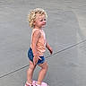 Ricki joined the competition — help win amazing prizes! toddler, child, curly_hair, smiling, standing, side_view, outdoor, concrete, garage_doors, footwear, pink_crocs, denim_shorts, tank_top, casual_clothing, sunlight, shadow, happy, young_child, walking, daytime