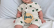 Leo joined the competition — help win amazing prizes! baby, cactus_pattern, child, cute, face, foot, four_months, hand, happy, indoors, infant, milestone, outfit, person, portrait, sitting, smiling, soft_lighting, white_bed, wooden_sign
