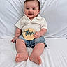 baby, child, smile, sitting, shirt, denim_shorts, wooden_sign, three_months, happy, indoors, couch, white, cute, portrait, infant, young_child, skin, feet, hand, face