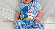 Leo is registered to the contest to win money with this photo: baby, infant, smiling, blue_clothing, hat, cute, sitting, white_background, child, happy, plaid_pattern, footwearless, indoors, soft_surface, portrait, bunny_design, headwear, small_child, cheerful, closeup