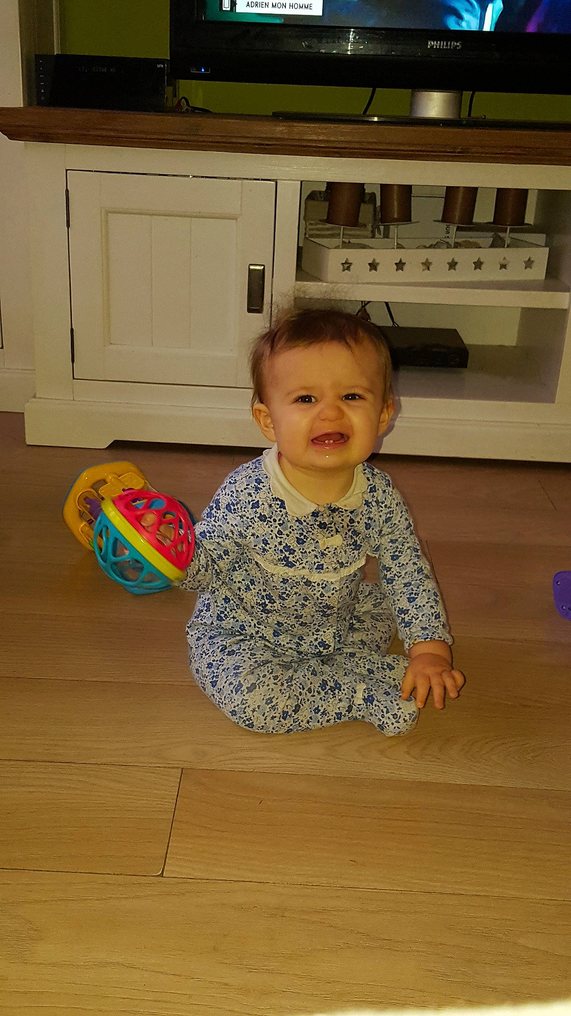 Maelys participe au concours pour gagner de l'argent avec cette photo : child, day, floor, flooring, fun, girl, infant, person, play, sitting, smile, standing, toddler, wood