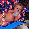 baby, bottle, chair, blanket, santa_claus_pattern, dog, blue_collar, carpet, indoor, child, cute, reclining, drinking, furniture, person, curly_hair, skin, relaxing, pet, date_stamp