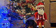 Hot participe au concours pour gagner de l'argent avec cette photo : dog, christmas_tree, christmas_decorations, ornaments, lights, snowman, toy_figure, santa_claus, wooden_floor, holiday, festive, indoor, decor, celebration, pet, christmas, tinsel, figurine, warm_lighting, cozy