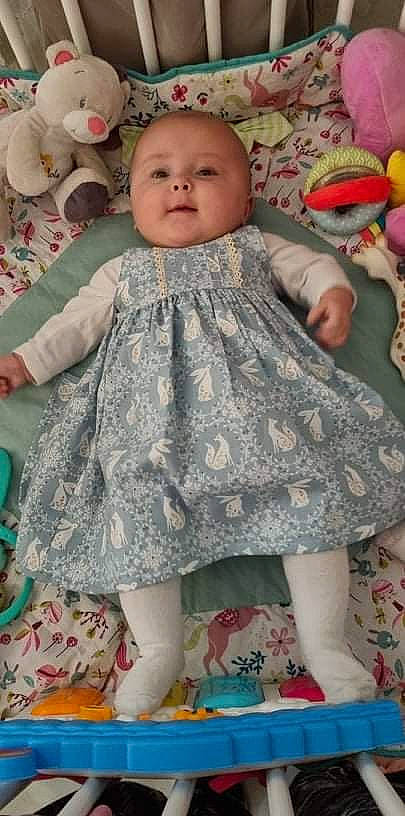 Jehanne participe au concours pour gagner de l'argent avec cette photo : arm, baby, baby_toddler_clothing, cheek, dress, eye, face, facial_expression, head, iris, one_piece_garment, organ, person, photograph, pink, product, skin, sleeve, smile, standing