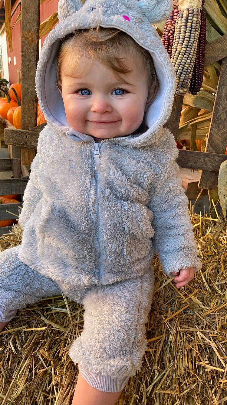 Alora is registered to the contest to win money with this photo: agriculture, baby, baby_toddler_clothing, child, face, fur, grass, happy, joy, outerwear, people_in_nature, person, photograph, pumpkin, sitting, skin, sleeve, smile, soil, toddler