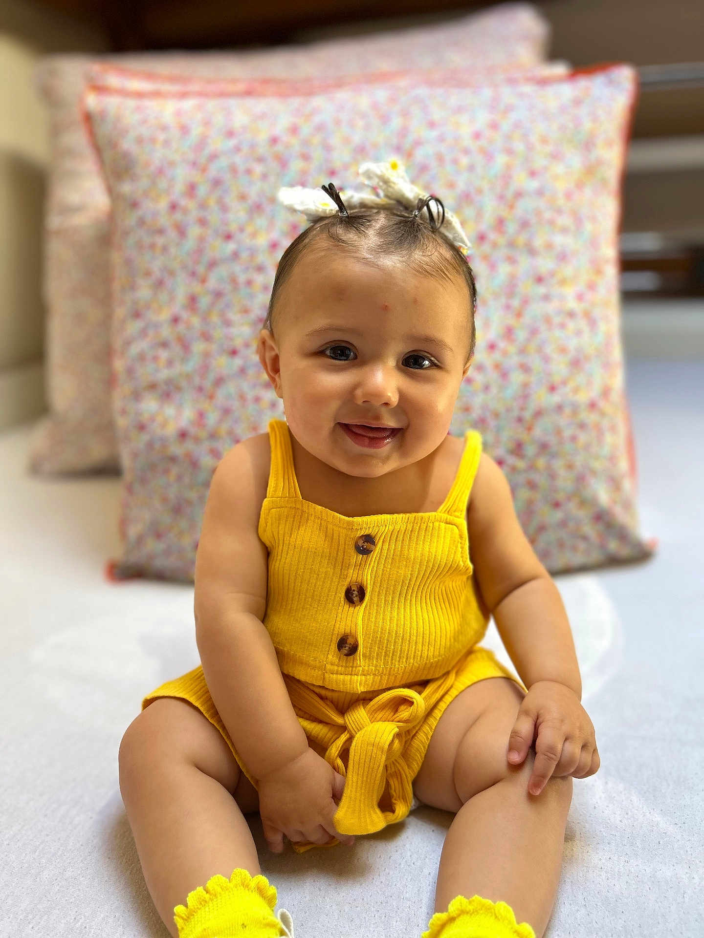 Maïllana a rejoint le concours — aidez-le/la à gagner de superbes lots ! baby, child, smiling, yellow_outfit, sitting, pillow, indoor, cute, happy, face, person, clothing, footwear, infant, portrait, baby_girl, fashion, soft_lighting, closeup, headband