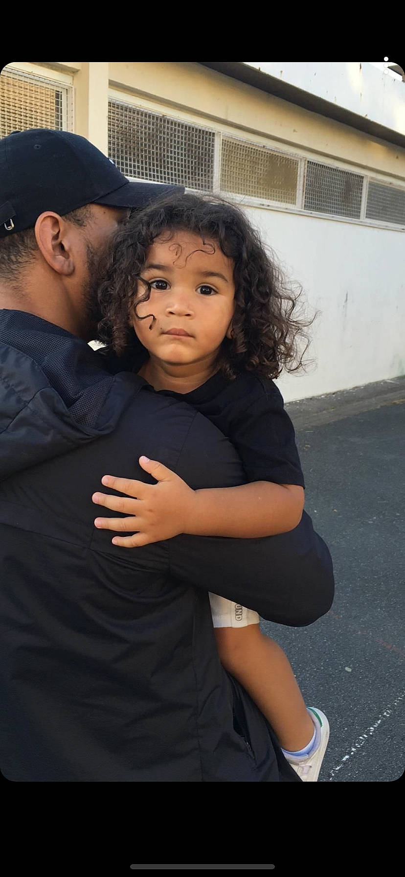 Jaden participe au concours pour gagner de l'argent avec cette photo : baseball_cap, black_hair, cap, child, event, eye, formal_wear, fun, gesture, happy, hug, joint, person, sandal, shoulder, sitting, sleeve, thumb, toddler, tradition