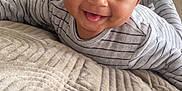 Malick participe au concours pour gagner de l'argent avec cette photo : baby, bed, blanket, child, cozy, curly_hair, cute, face, happy, indoors, infant, lying_down, person, portrait, smiling, soft_light, striped_clothing, texture, tongue_out, young_child