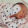 newborn, baby, sleeping, blanket, pink, onesie, heart_pattern, infant, peaceful, cozy, soft, cute, child, face, skin, head, hand, bed, fabric, closeup