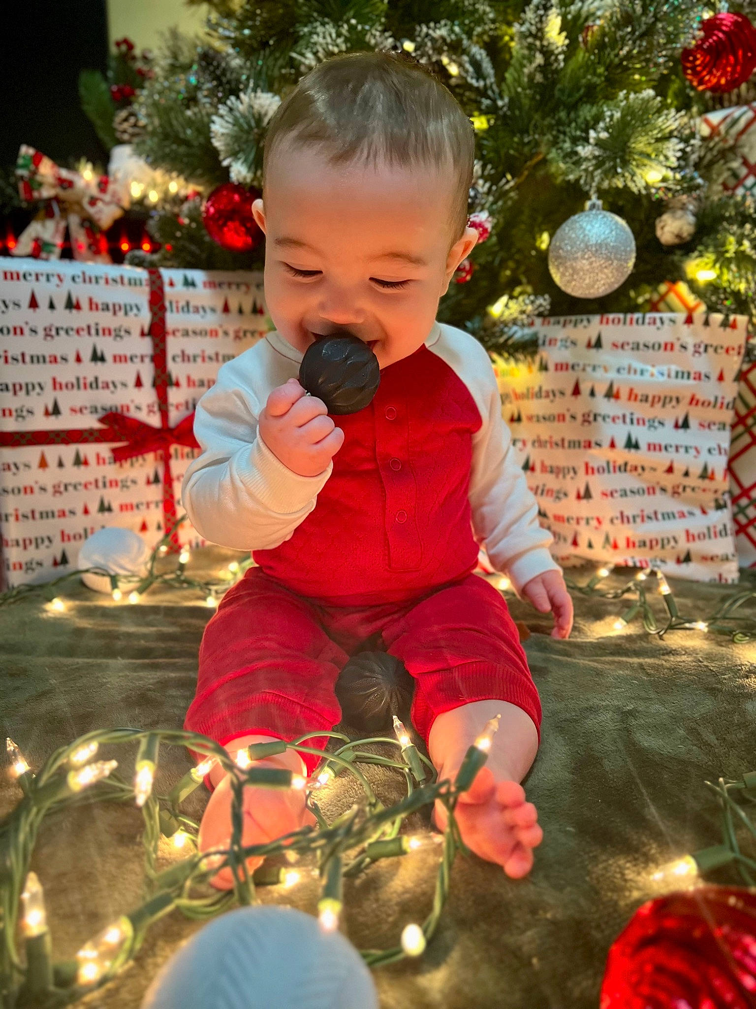 Lennox is registered to the contest to win money with this photo: baby, child, christmas_decoration, christmas_ornament, christmas_tree, event, facial_expression, fun, happy, holiday, holiday_ornament, human_body, light, lighting, ornament, people_in_nature, person, red, snapshot, standing