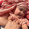 baby, infant, child, smiling, portrait, closeup, pink, blanket, headwrap, clothing, hand, adult_hand, cuddling, cozy, indoors, face, eyes, mouth, happy, soft_lighting