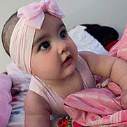 Ailannys is registered to the contest to win money with this photo: baby, bed, bedding, bedroom, blanket, bow, child, close_up, colorful, cozy, curious, eyes, face, headband, indoors, infant, looking_up, pink, portrait, sitting