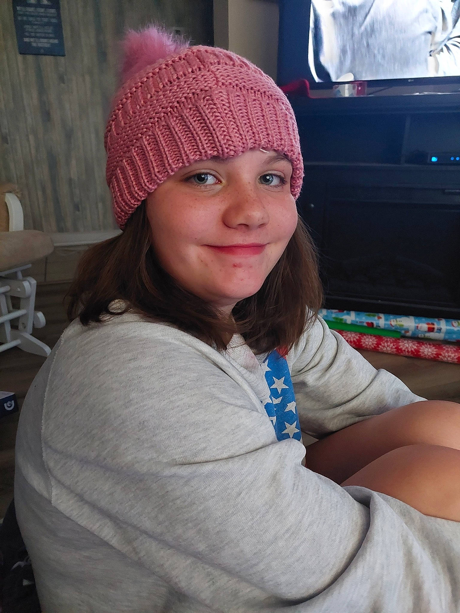 Lillian is registered to the contest to win money with this photo: beanie, blond, brown_hair, cap, cool, electric_blue, fashion_accessory, fun, headwear, human_leg, joy, knit_cap, lip, long_hair, magenta, person, sitting, smile, street_fashion, television