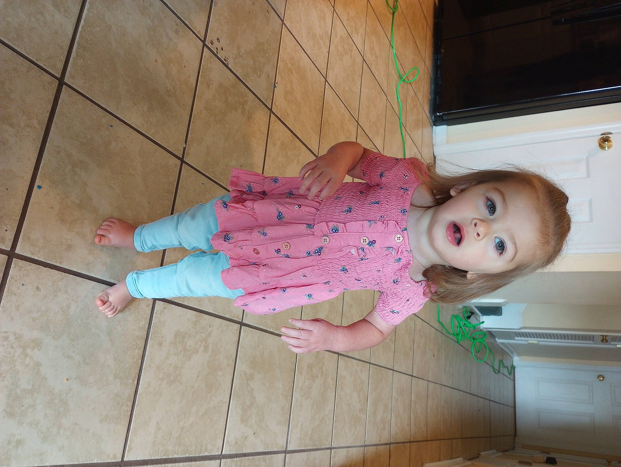 Alaina is registered to the contest to win money with this photo: baby, baby_toddler_clothing, cheek, child, floor, flooring, foot, fun, hardwood, human_leg, leg, magenta, pattern, person, pink, sitting, skin, smile, sock, toddler