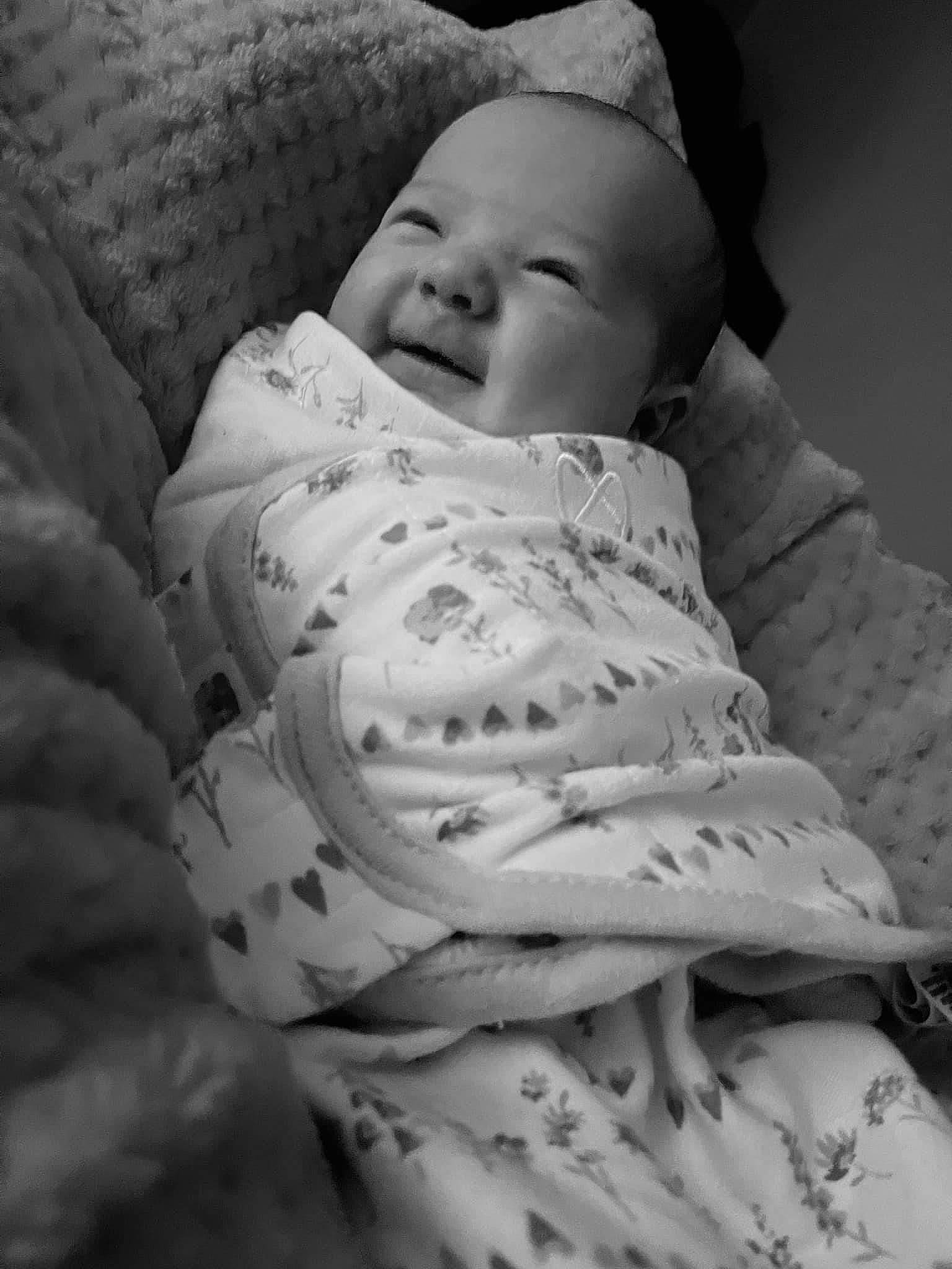 Rosalie is registered to the contest to win money with this photo: baby, baby_toddler_clothing, bedtime, cheek, child, comfort, face, happy, linens, monochrome, monochrome_photography, pattern, person, portrait_photography, room, skin, sleep, sleeve, smile, textile
