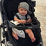 baby, stroller, cap, child, foot, barefoot, black_stroller, graco, striped_shirt, sitting, infant, cute, playful, expression, clothing, seatbelt, blanket, indoors, floor, person