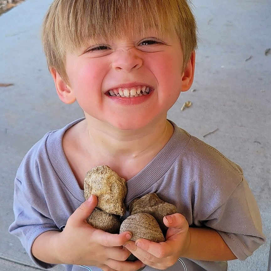 Mavrik joined the competition — help win amazing prizes! black_shoes, blonde_hair, boy, casual_clothing, child, concrete, daylight, footwear, grass, happy, holding, nature, outdoor, person, playful, porch, rocks, shorts, smiling, tshirt