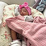 baby, sleeping, pink_blanket, headband, floral_quilt, plush_toy, elephant_plush, footwear, white_shoes, cozy, indoors, child, smile, comfort, blanket, cute, resting, soft_texture, happy, infant