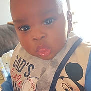 Deangelo joined the competition — help win amazing prizes! baby, child, infant, face, bib, clothing, mickey_mouse, blue_outfit, indoor, portrait, closeup, curious, young_child, cute, expression, home, soft_light, person, smiling, head