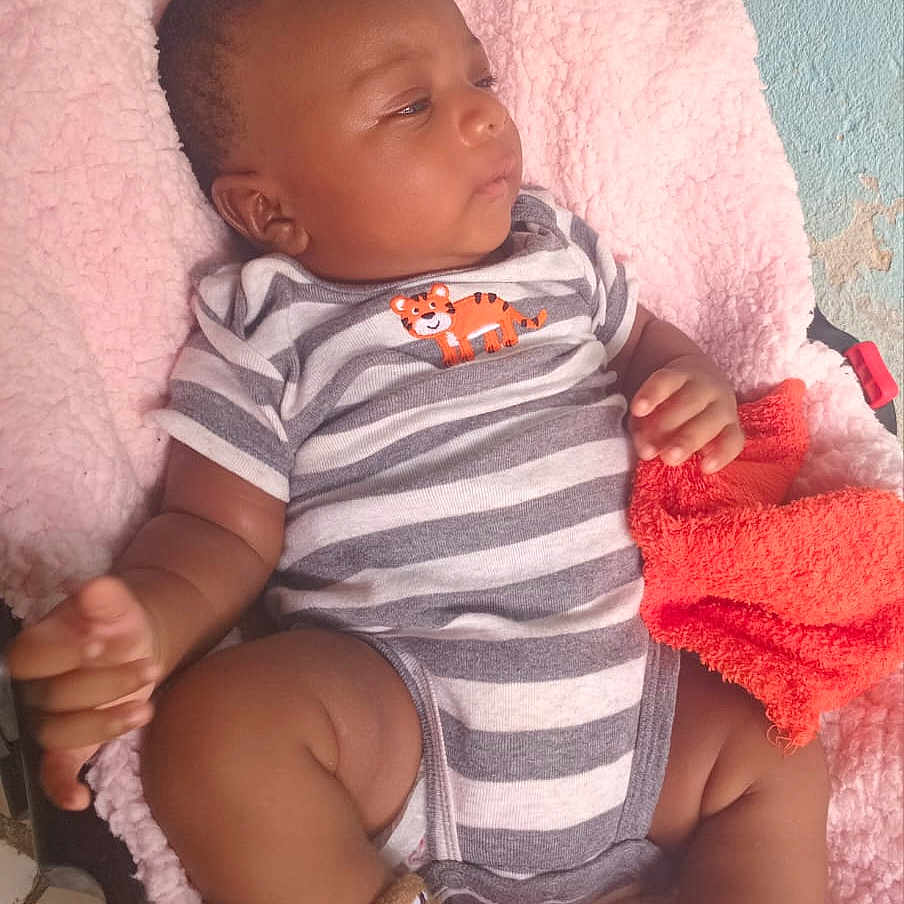 Asaël participe au concours pour gagner de l'argent avec cette photo : baby, bedding, car_seat, chubby_legs, cute, fabric, face, hand, indoor, infant, looking_away, onesie, orange_towel, pink_blanket, portrait, relaxed, socks, stripes, tiger_patch, wall_texture