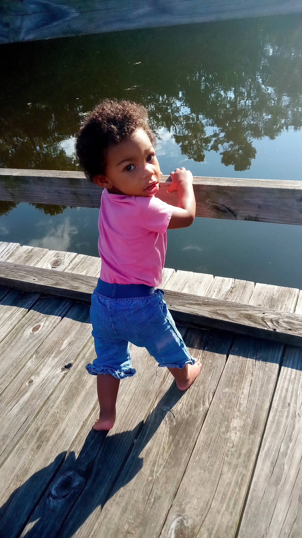 Madelynn is registered to the contest to win money with this photo: azure, baby, barefoot, dock, foot, fun, happy, human_leg, leg, leisure, morning, people_in_nature, person, shorts, standing, thumb, toddler, tree, waist, water