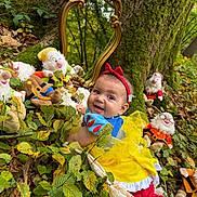 Augustine participe au concours pour gagner de l'argent avec cette photo : baby, child, costume, cute, dwarfs, fallen_leaves, forest, green_leaves, mirror, moss, nature, outdoor, playful, plush_toys, red_headband, smiling, snow_white, tree, whimsical, yellow_dress