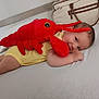 Augustine a rejoint le concours — aidez-le/la à gagner de superbes lots ! baby, bed, child, cozy, cute, face, furniture, happy, head, indoor, infant, lobster, lying_down, person, playful, plush_toy, smile, soft_toy, white_bed, yellow_onesie