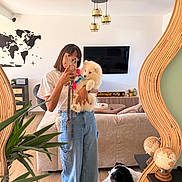 Caïpi participe au concours pour gagner de l'argent avec cette photo : woman, person, dog, puppy, fluffy_dog, black_and_white_dog, tennis_ball, mirror_selfie, smartphone, living_room, interior, sofa, television, plant, world_map, pendant_lights, wooden_floor, globes, fashion, pet