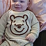 baby, smiling, pajamas, bear_design, pink_pillow, couch, child, infant, clothing, cute, relaxed, indoors, soft_fabric, seated, portrait, happy, young_child, face, cozy, comfort