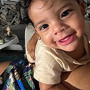Isaiah joined the competition — help win amazing prizes! toddler, child, smiling, face, eyes, curly_hair, indoor, living_room, couch, cushion, baby_toys, person, human_arm, clothing, holding, closeup, happy, skin, portrait, infant