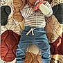 baby, child, bottle, milk, striped_shirt, blue_pants, barefoot, mat, patterned_mat, indoor, cute, lying_down, hands, feet, infant, portrait, casual_clothing, natural_light, relaxed, young