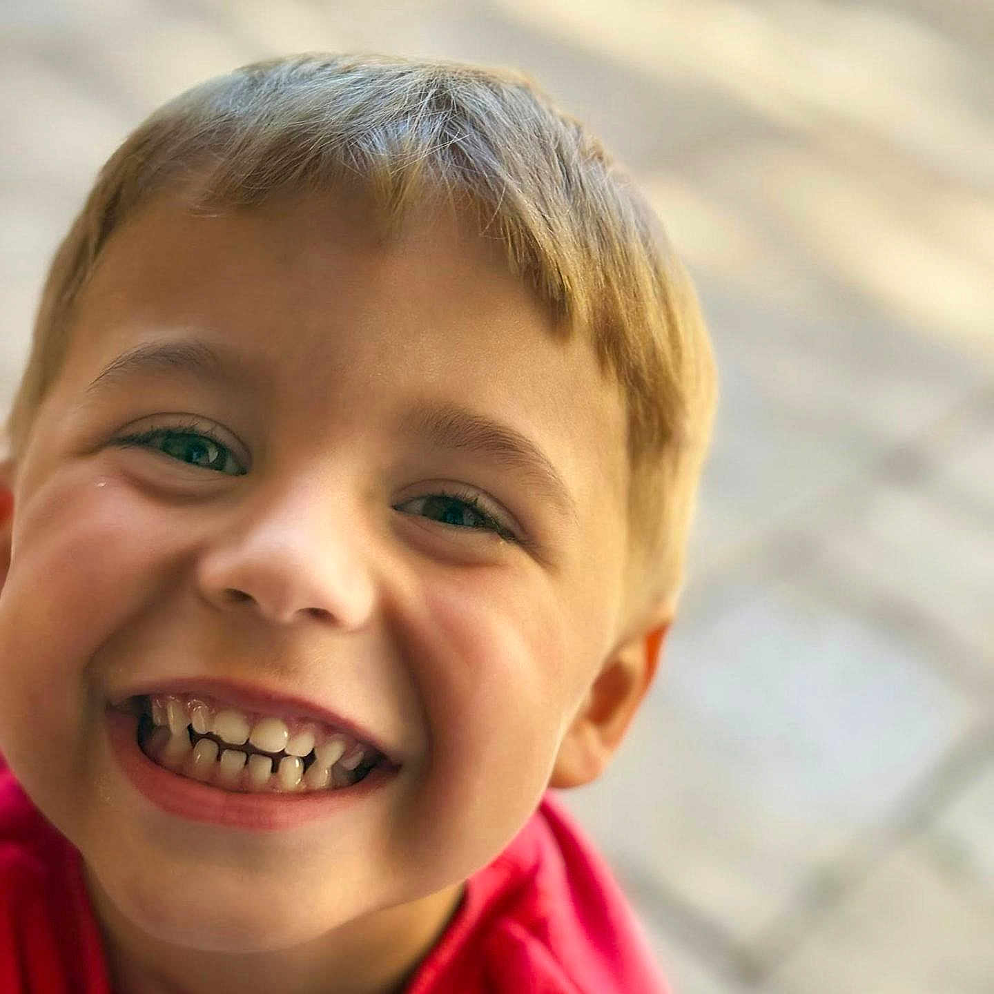 Aaron a rejoint le concours — aidez-le/la à gagner de superbes lots ! blond_hair, boy, casual_clothing, cheerful, child, childhood, closeup, cute, eyes, face, happy, joyful, natural_light, outdoor, person, portrait, red_shirt, smiling, teeth, young