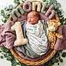 Maverick is registered to the contest to win money with this photo: newborn, baby, sleeping, portrait, basket, wicker, giraffe, stuffed_animal, plush_toy, number_one, felt_letters, blanket, swaddle, greenery, eucalyptus, floral_arrangement, nursery, cozy, peaceful, photography