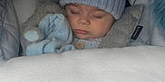 Aaron-Jay is registered to the contest to win money with this photo: baby, sleeping, knit_hat, blanket, plush_toy, blue, cozy, car_seat, child, infant, cute, soft_toys, peaceful, nap, warm_clothing, mobile, indoors, resting, cushion, portrait