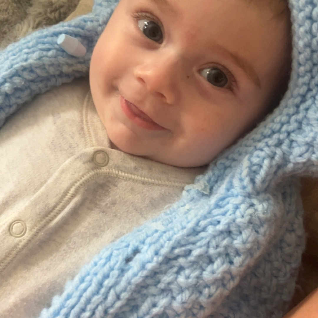 Aaron-Jay is registered to the contest to win money with this photo: baby, blue, child, closeup, cozy, cute, eyes, face, fuzzy, happy, hood, indoor, infant, knitted_blanket, lying_down, portrait, skin, smile, soft_texture, warm_clothing
