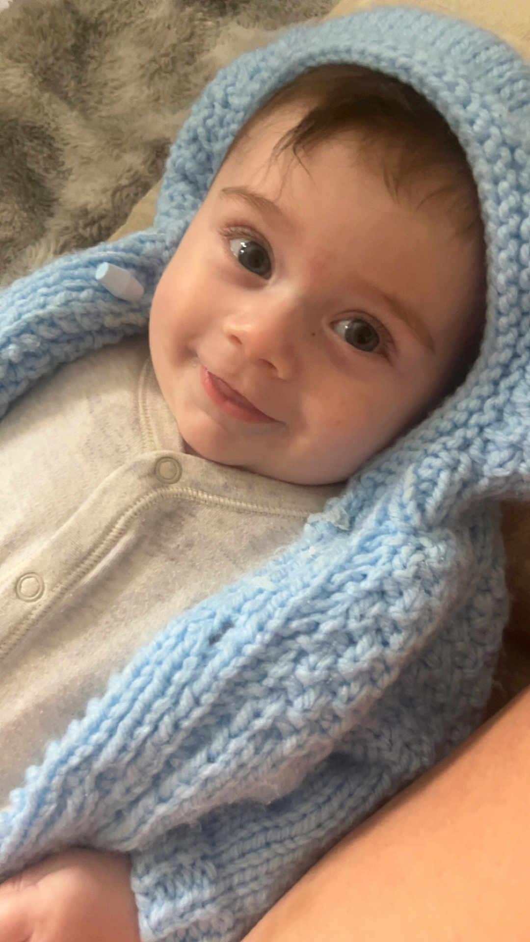 Aaron-Jay is registered to the contest to win money with this photo: baby, child, infant, knitted_blanket, blue, hood, smile, face, eyes, soft_texture, warm_clothing, cozy, cute, lying_down, closeup, skin, happy, portrait, indoor, fuzzy