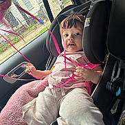 Arleth is registered to the contest to win money with this photo: toddler, child, car_seat, pink_ribbons, rain, car_window, headband, pink_clothing, seatbelt, indoors, raindrops, cute, baby, car_interior, child_safety, curious, soft_blanket, casual_clothing, portrait, young_child