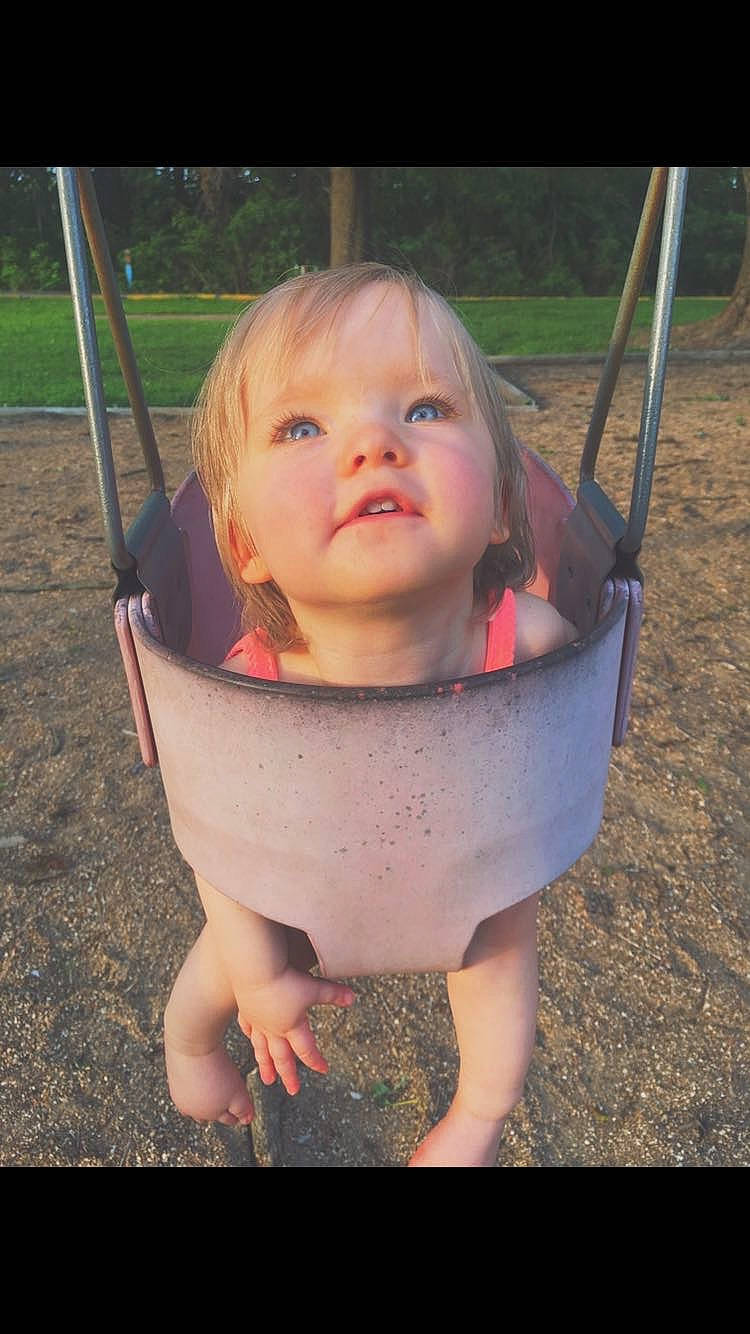 Joyce is registered to the contest to win money with this photo: baby, cheek, child, eye, fun, grass, outdoor_play_equipment, person, pink, play, playground, public_space, skin, smile, swing, toddler