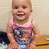 Tallulah is registered to the contest to win money with this photo: baby, babylaughing, bathroom, bodypart, clothing, face, happy, head, indoors, mouth, pants, person, photography, portrait, sitting, smile, swimwear, t_shirt, tanktop, teeth