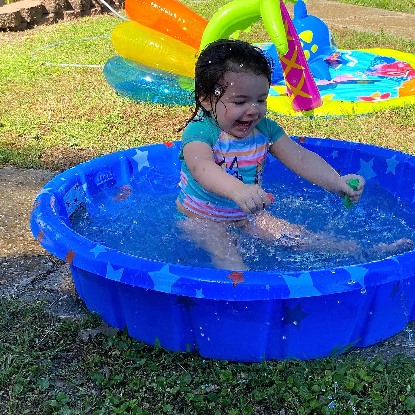 Melania Martin is registered to the contest to win money with this photo: backyard, blue, child, colorful, cute, fun, grass, green, happy, inflatable, outdoor, play, pool, smile, splashing, summer, sunlight, toddler, toy, water