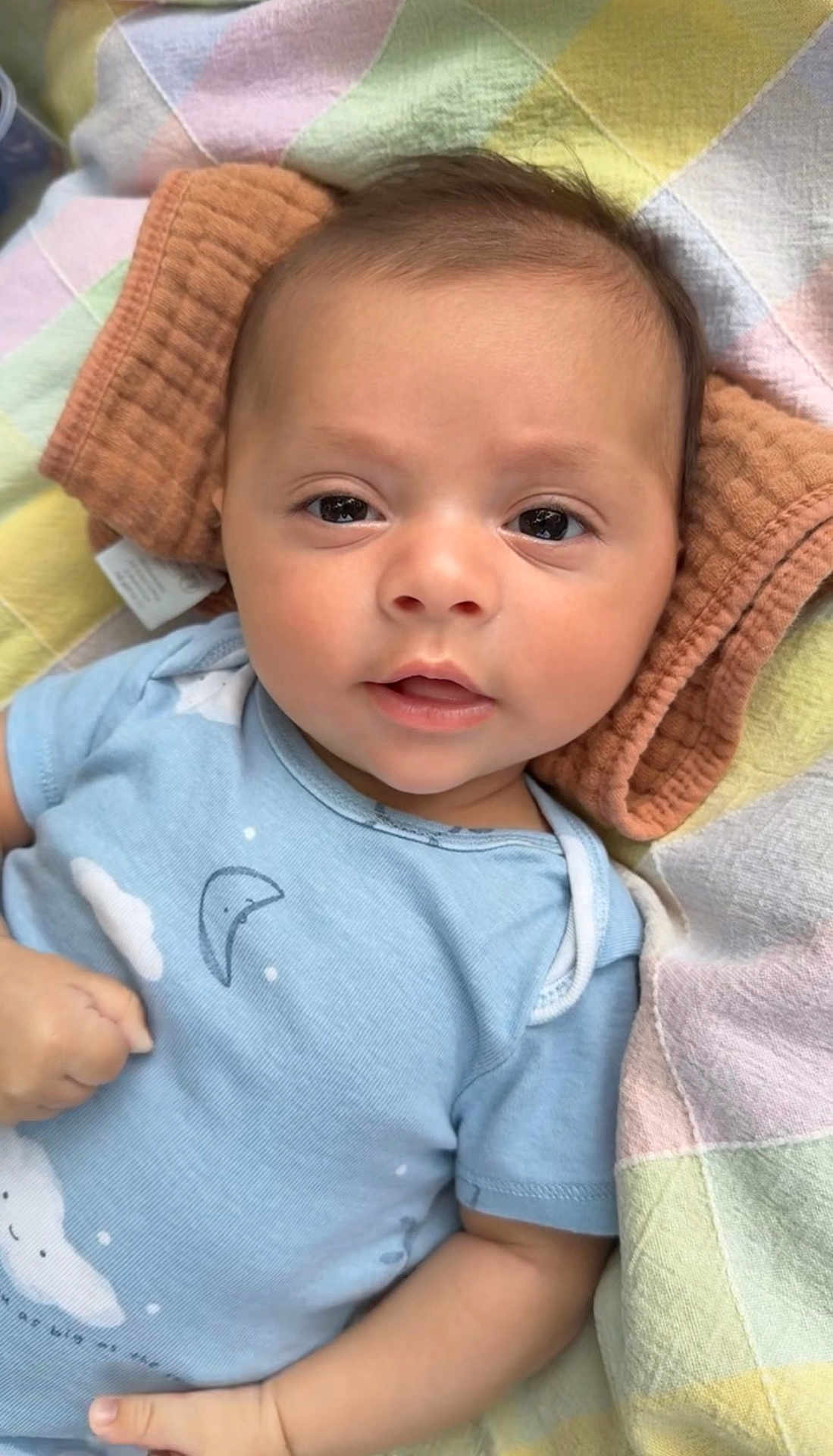 Jayden joined the competition — help win amazing prizes! baby, infant, face, portrait, blue_onesie, blanket, towel, hand, expression, lying_down, skin, head, eyes, mouth, clothing, comfort, soft_texture, indoors, cute, child