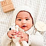 Sardonyx Elijah is registered to the contest to win money with this photo: baby, infant, knit_clothing, bonnet, crocheted_toy, teddy_bear, wooden_blocks, 3_months, blanket, soft_texture, cute, child, portrait, hands, face, lying_down, cozy, warm, indoor, newborn