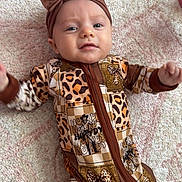 Isla joined the competition — help win amazing prizes! baby, infant, child, onesie, headband, brown, animal_print, patterned_rug, floor, hands, face, blue_eyes, cute, lying_down, indoor, soft_light, expression, clothing, young, person