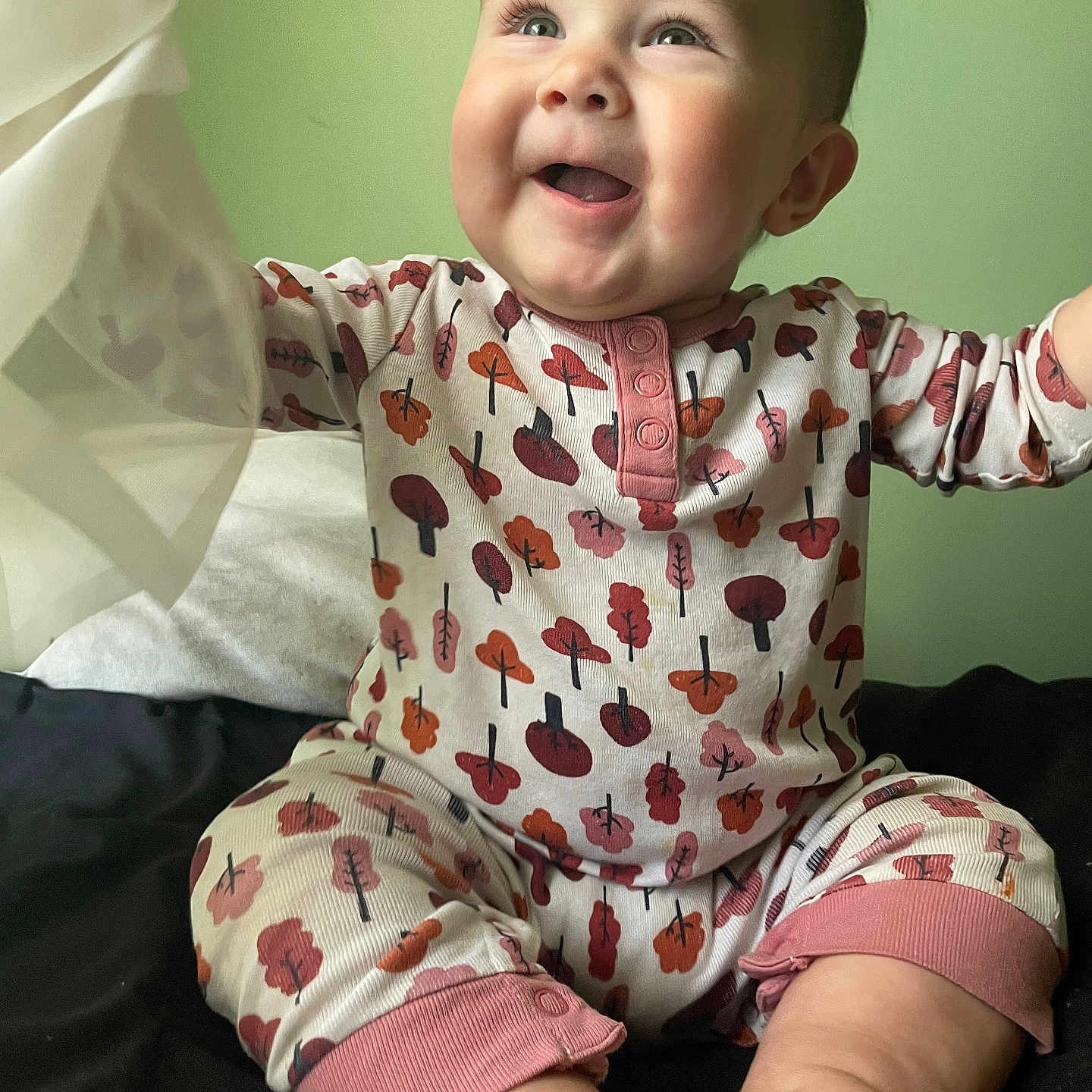 Piper joined the competition — help win amazing prizes! arms_raised, baby, bed, blanket, child, cute, expression, face, foot, green_wall, happy, indoors, infant, joyful, pajamas, patterned_clothing, portrait, sitting, skin, smile